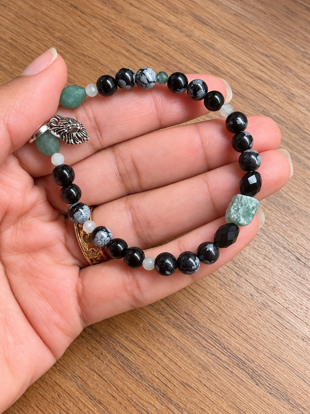 Le Gardien du Territoire, bracelet en aventurine verte et obsidiennes avec breloque loup, présenté dans la main